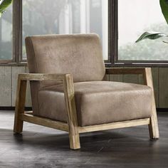 a brown chair sitting in front of a window next to a potted green plant