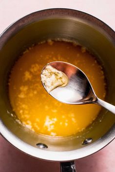 a spoon in a pot filled with liquid and some bread crumbs on the side