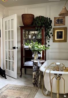 a white bath tub sitting in a bathroom next to a wooden cabinet and potted plant