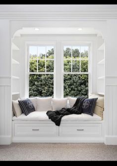 a white window seat with pillows on it