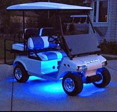 an electric golf cart is lit up with blue lights in front of a house at night