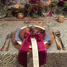 a place setting with flowers and silverware on the table, ready to be served