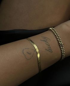 a woman's arm with a gold bracelet and name tattoo on the side of her arm