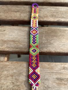 a colorful bracelet sitting on top of a wooden bench