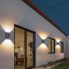 an exterior view of a modern home with lights on the outside wall and lawn area