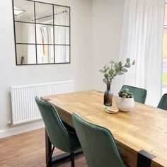 a dining room table with green chairs and a mirror on the wall