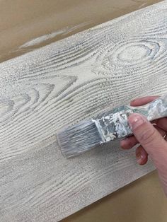 a person holding a paintbrush over a wooden plank