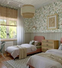 two beds in a room with floral wallpaper