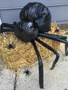 a large black spider statue sitting on top of hay covered ground next to a door