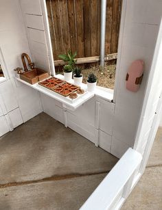 a window sill in the corner of a house with potted plants on it