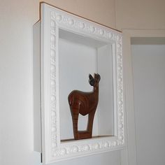 a wooden horse in a white frame on the wall