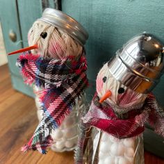 two snowmen are sitting next to each other in glass jars with lids on them