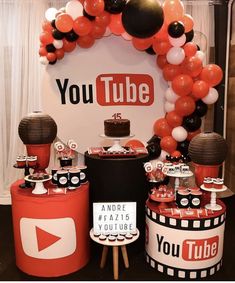 a table topped with red, black and white balloons next to a youtube logo sign