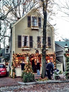 people are standing in front of a house decorated for christmas