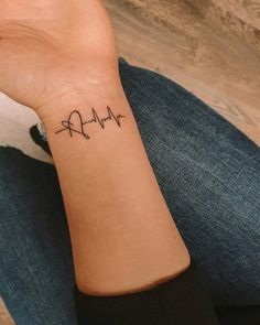 a woman's wrist with a heartbeat tattoo on it