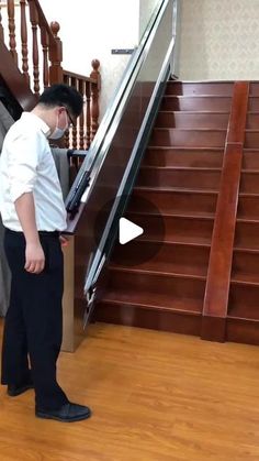 a man wearing a face mask standing in front of an escalator and stairs