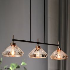 three clear glass lights hanging from a metal bar