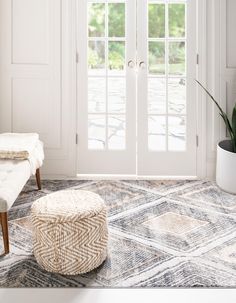 a living room with white doors and an ottoman