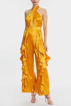 Every vacation wardrobe deserves a pop of color. The Merk's best-selling jumpsuit is ready to be yours, now offered in this new ever-so-rich cruise color. This mango goldish jumpsuit is expertly draped in floral jacquard fabric, featuring cascading ruffles down the legs, a keyhole cut-out, and a criss-cross wrap halter neck. We love the floral pattern woven right into this silk-like luxe jacquard fabric... The Merk's elegance is all in the details. Glamorous Satin Jumpsuits And Rompers For Spring, Glamorous Spring Satin Jumpsuit, Gold Jumpsuits And Rompers For Summer Evenings, Gold Jumpsuits And Rompers For Evening, Summer, Gold Evening Jumpsuits And Rompers For Summer, Chic Gold Sleeveless Jumpsuits And Rompers, Sleeveless Gold Jumpsuits For Spring, Jumpsuit Mango, Mango Jumpsuit