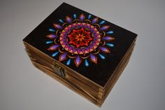 a wooden box with an intricate design painted on the front and sides, sitting on a white surface