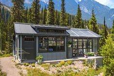 a small building in the middle of a forest with mountains in the backgroud