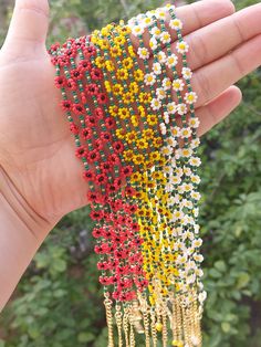 a hand is holding three bracelets made out of beaded beads and chains with flowers on them