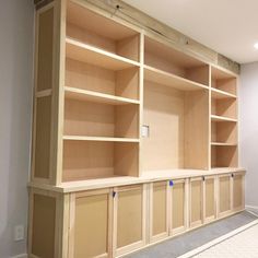 an unfinished bookcase with no doors is being built into the wall in this room