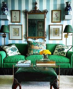 a living room with green couches and pictures on the wall