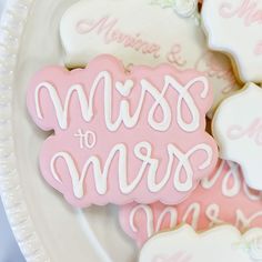 decorated cookies on a plate with the words mom of bride and groom written in white frosting