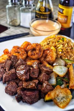 a white plate topped with meat and veggies covered in sauce next to beer bottles