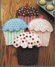 four cupcakes are sitting on the table next to some muffins and an oven mitt