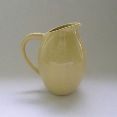 a cream colored pitcher is sitting on a white surface