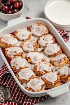 a pan filled with cinnamon rolls on top of a red and white checkered table cloth