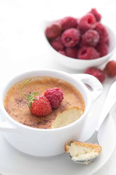 there is a bowl of pudding with raspberries on the side