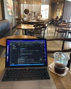 an open laptop computer sitting on top of a wooden table next to a cup of coffee