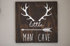 a wooden sign that says little man cave with deer antlers on the front and back