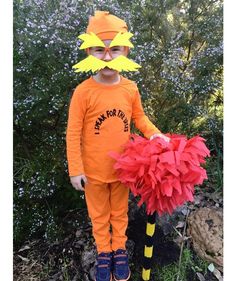 a young boy in an orange cat costume holding a fake red and yellow pom - pom