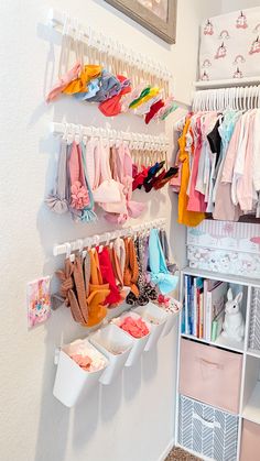 a closet filled with lots of baby clothes and hanging racks on the wall next to it