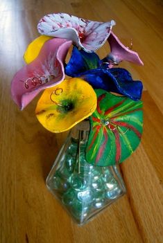 a glass vase filled with colorful flowers on top of a wooden table