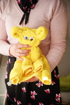 a woman is holding a yellow teddy bear