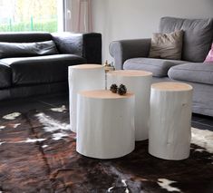 two white tables sitting on top of a rug in front of a gray couch and loveseat