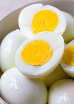 three hard boiled eggs in a bowl with yellow paste on the yolk and one has an egg shell