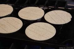 four uncooked pizzas sitting on top of an oven