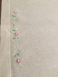 a table cloth with flowers and leaves embroidered on the side, sitting on a wooden surface