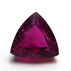 a pink triangle shaped gems on a white surface with the top half cut off to show it's lust