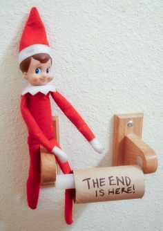 an elf is hanging on the wall with a roll of toilet paper in his hand