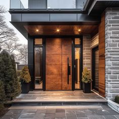 the front entrance to a modern home with two large doors and lights on each side