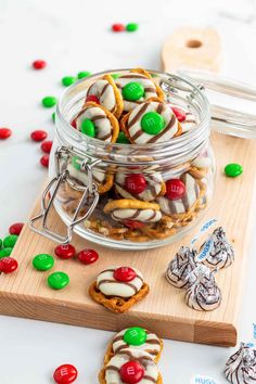 a jar filled with cookies and candy on top of a wooden cutting board next to other candies