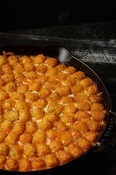 a pan filled with tater tots sitting on top of a stove next to a wooden table