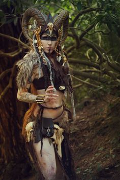 a woman with horns and makeup standing in the woods